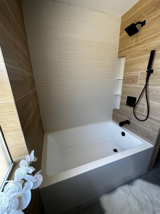 picture of a newly remodeled bathroom with new bathtub and laminate wall backsplash